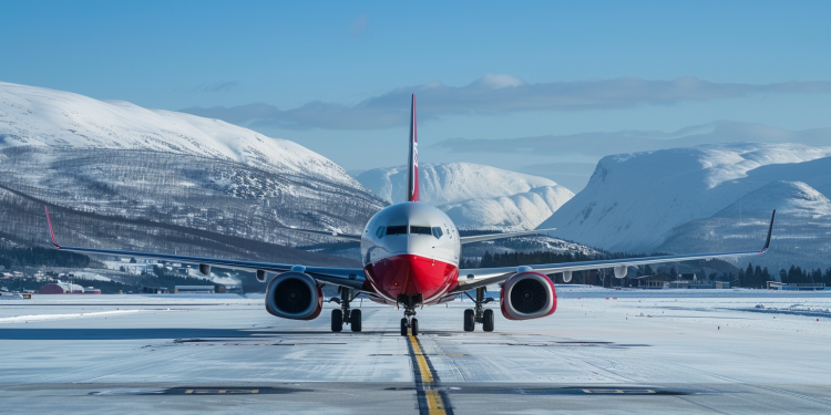 Norwegian Air Shuttle-Flugzeug rollt auf schneebedecktem Rollfeld mit Bergen im Hintergrund