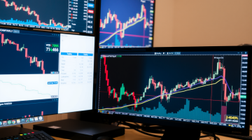 Analystenarbeitsplatz mit Aktiencharts auf Monitoren